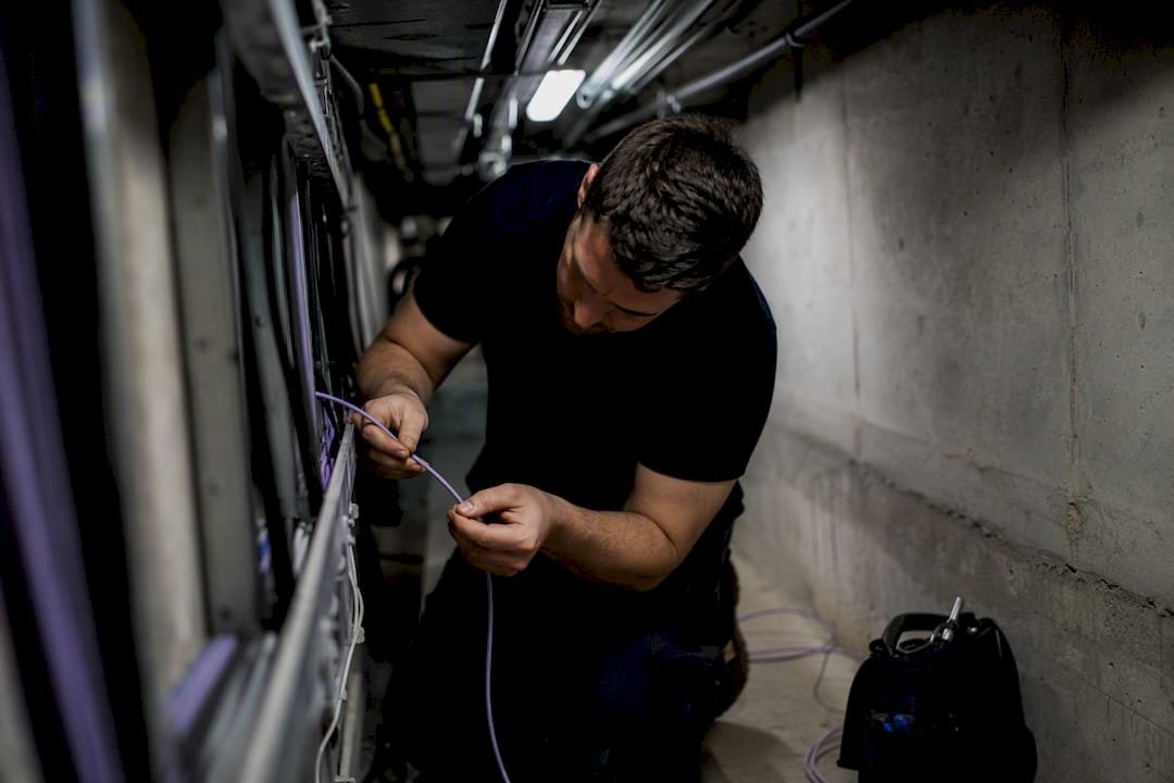 Technician feeding fibre optic cable in building