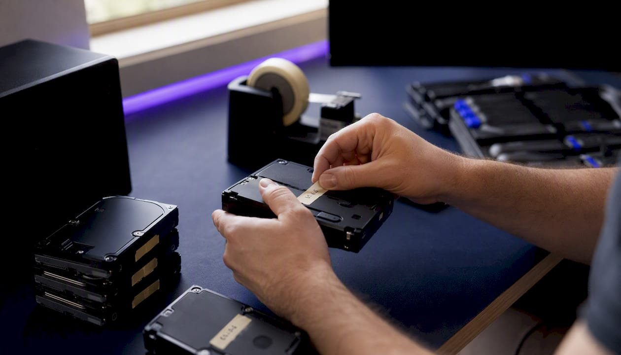 Hands labeling NAS hard drives before removal