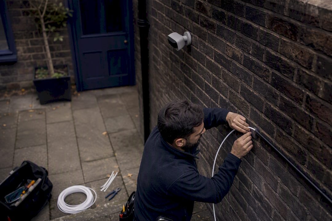 Technician routing wired PoE cable outdoors